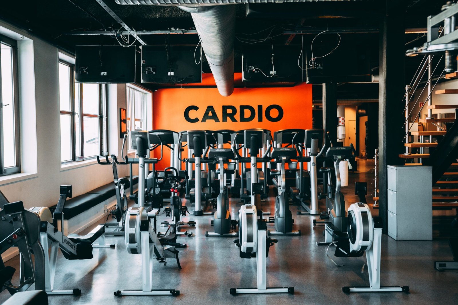 Kondisjonsavdelingen med tredemøller og romaskiner under et oransje Cardio-skilt